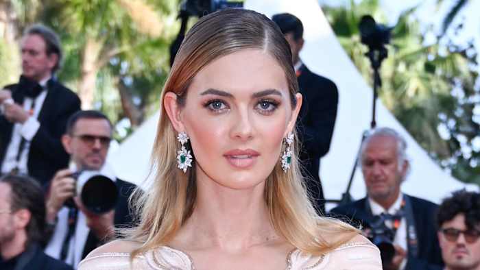 Megan Williams poses in a pale pink and cream dress and silver drop earrings.